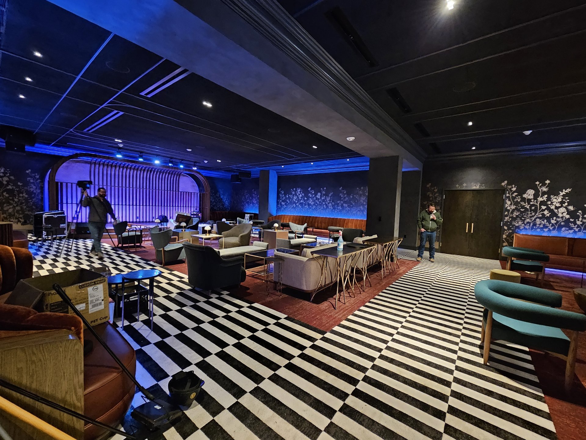 Music lounge — full room view with walnut stage backdrop and checkerboard floor