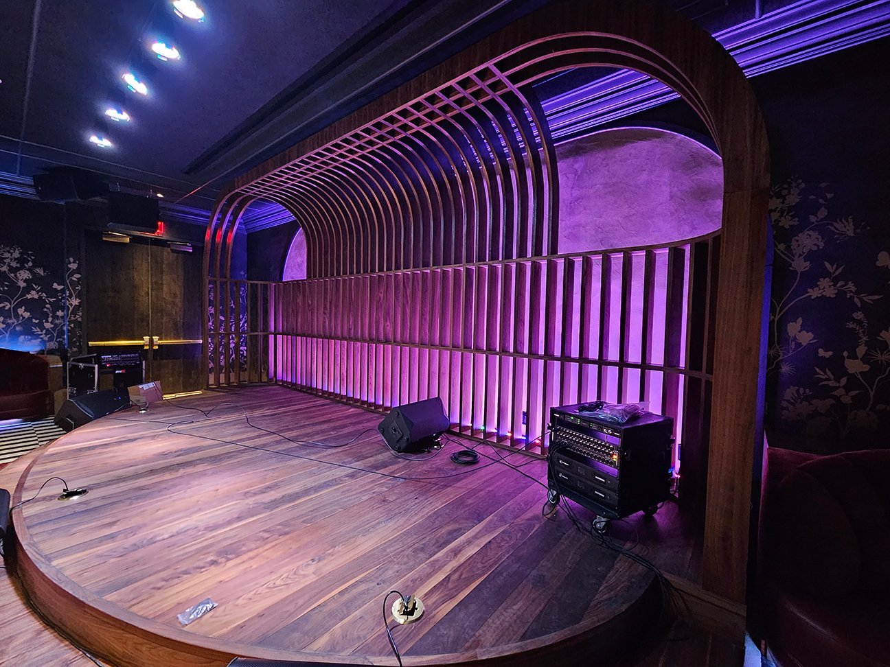 Music lounge — walnut stage and arched backdrop with purple lighting