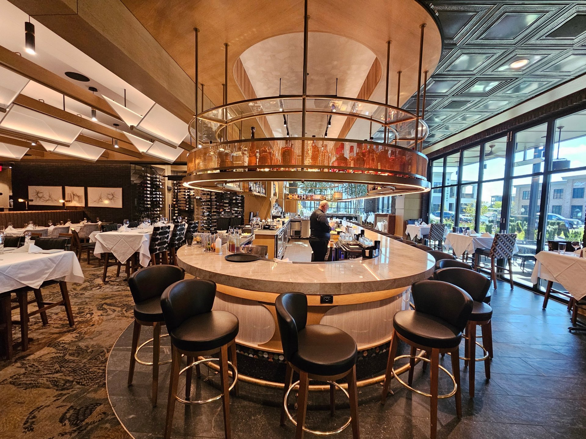 Ruth's Chris main bar — round island bar with suspended brass shelf and dining room