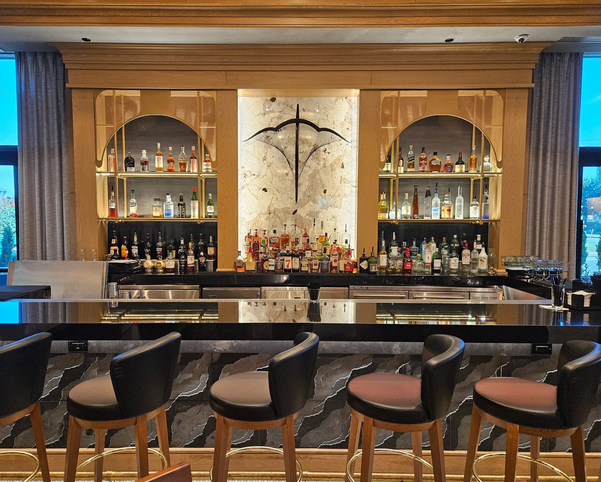 Ruth's Chris back bar — black marble front with brass foot rail and bottle display